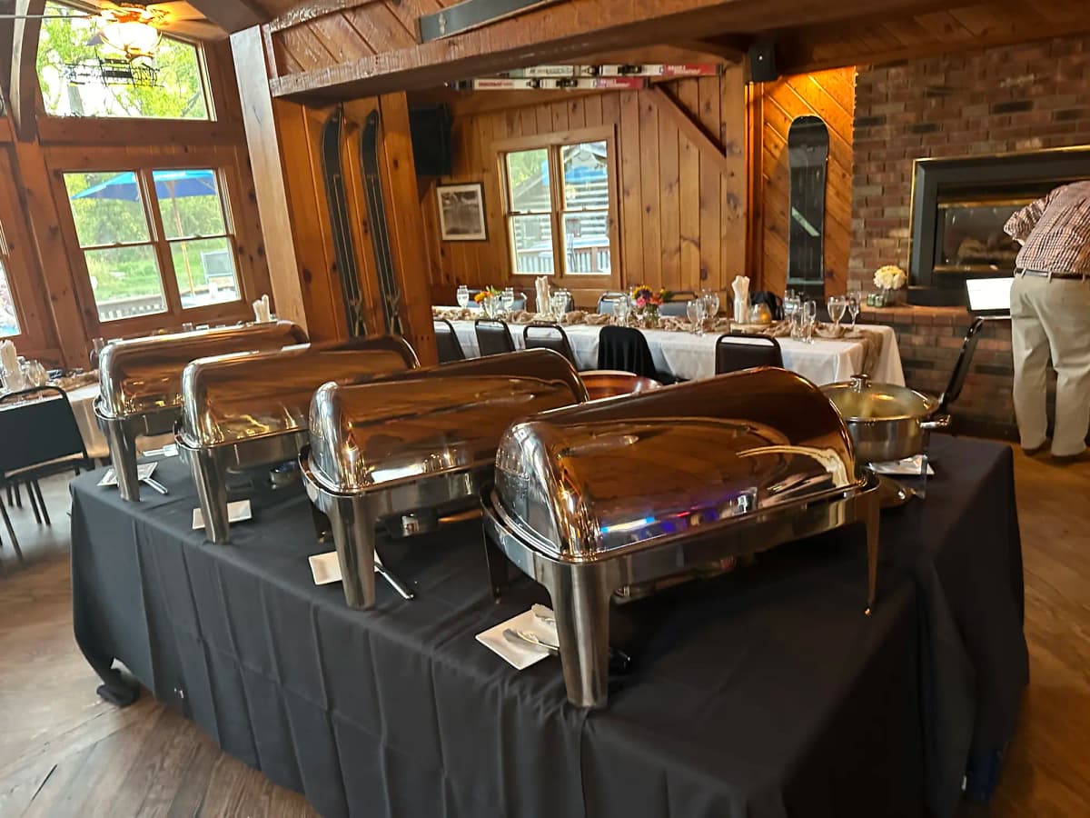 Indoor lodge event with chafing dishes on black-skirted tables