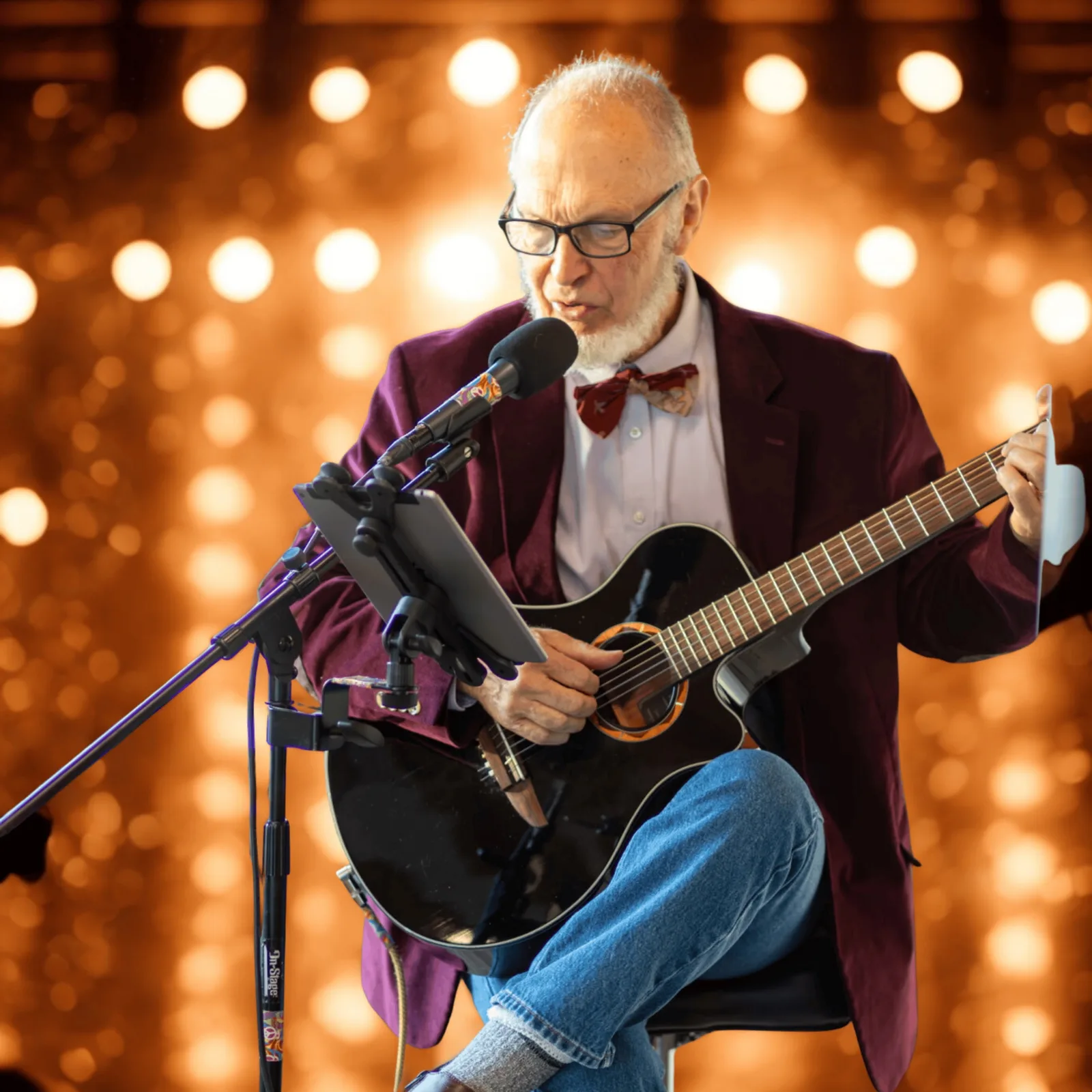 Bruce Wayne McLellan singing and playing an acoustic guitar at a microphone