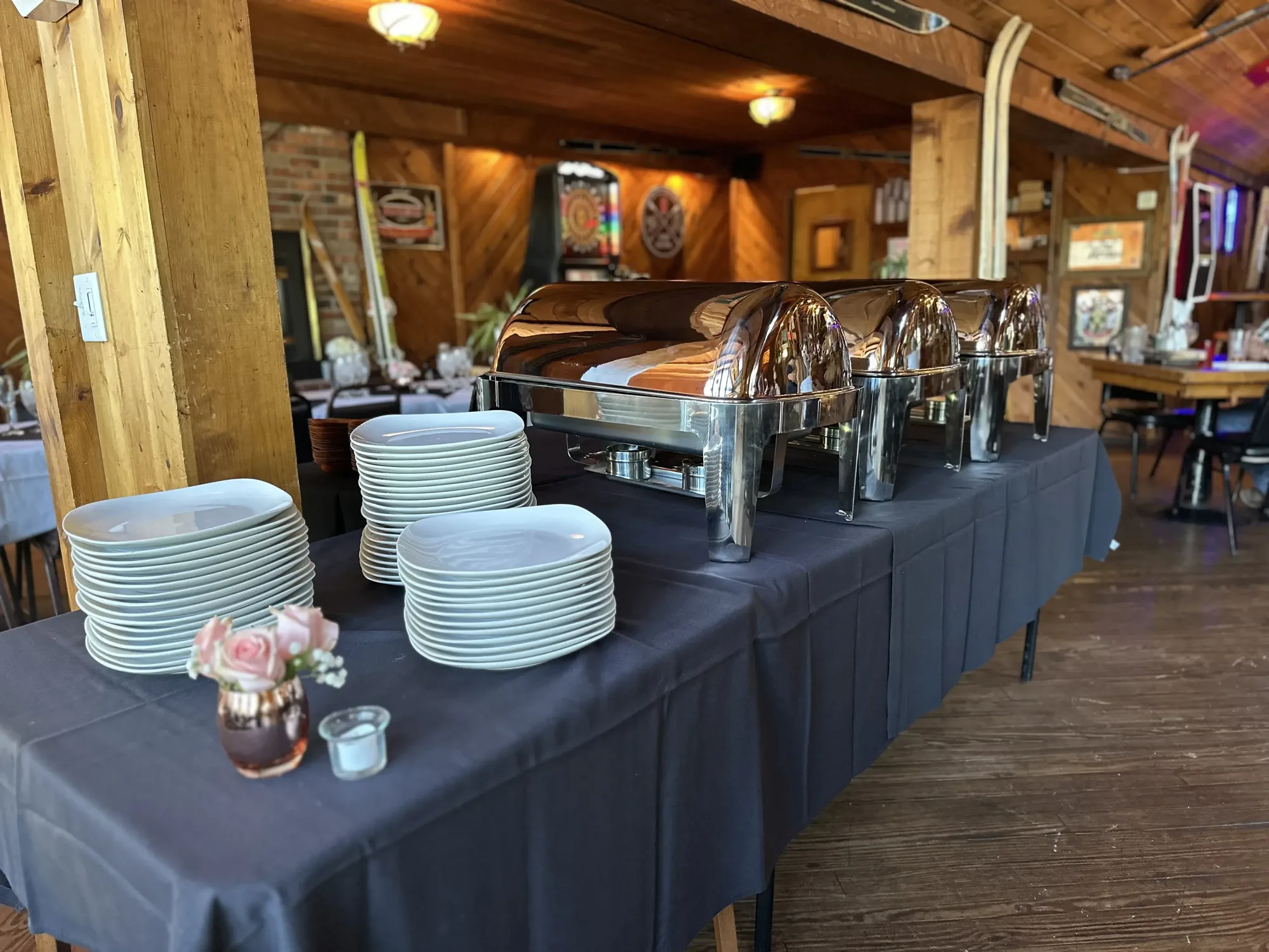 Buffet table with chafing dishes, stacked plates and pink roses in the lodge dining room