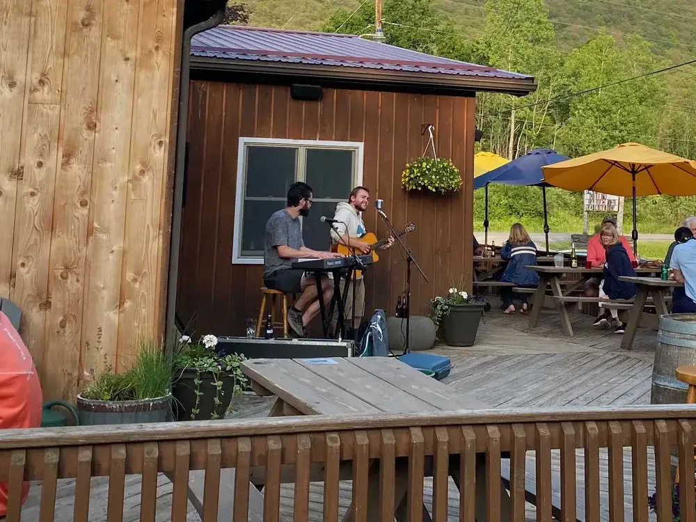 Duo playing keyboard and guitar on the deck beside the bar as guests dine under umbrellas